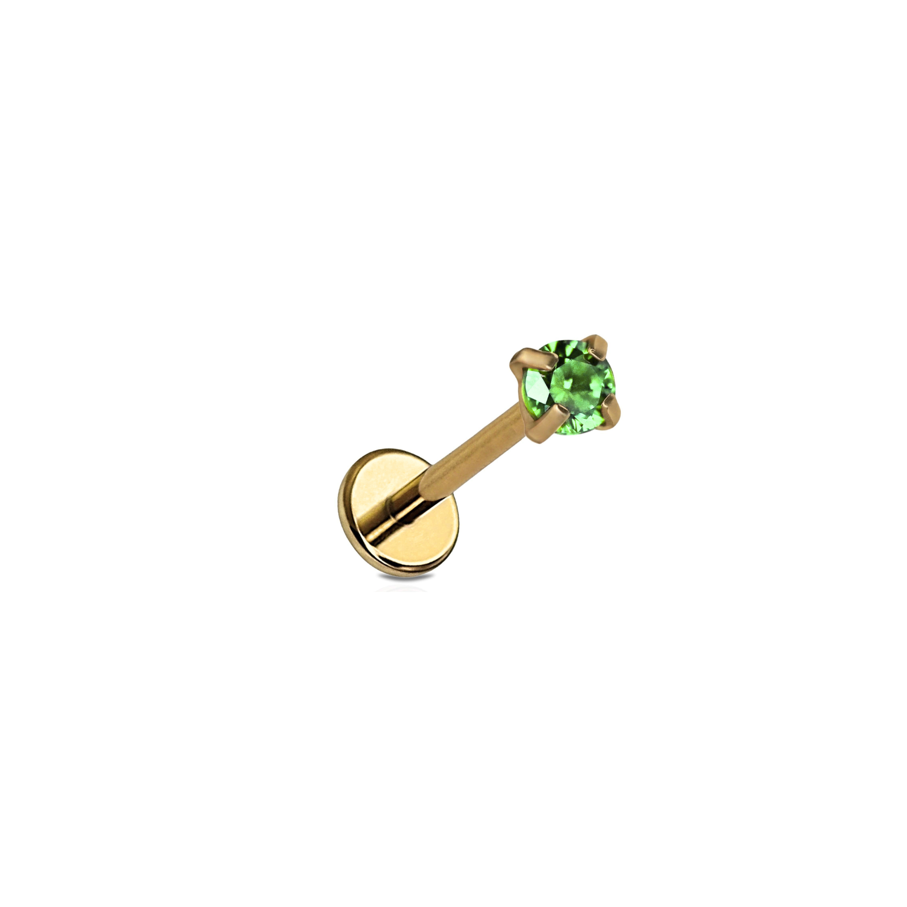 Gold lip ring with a green gemstone on a white background
