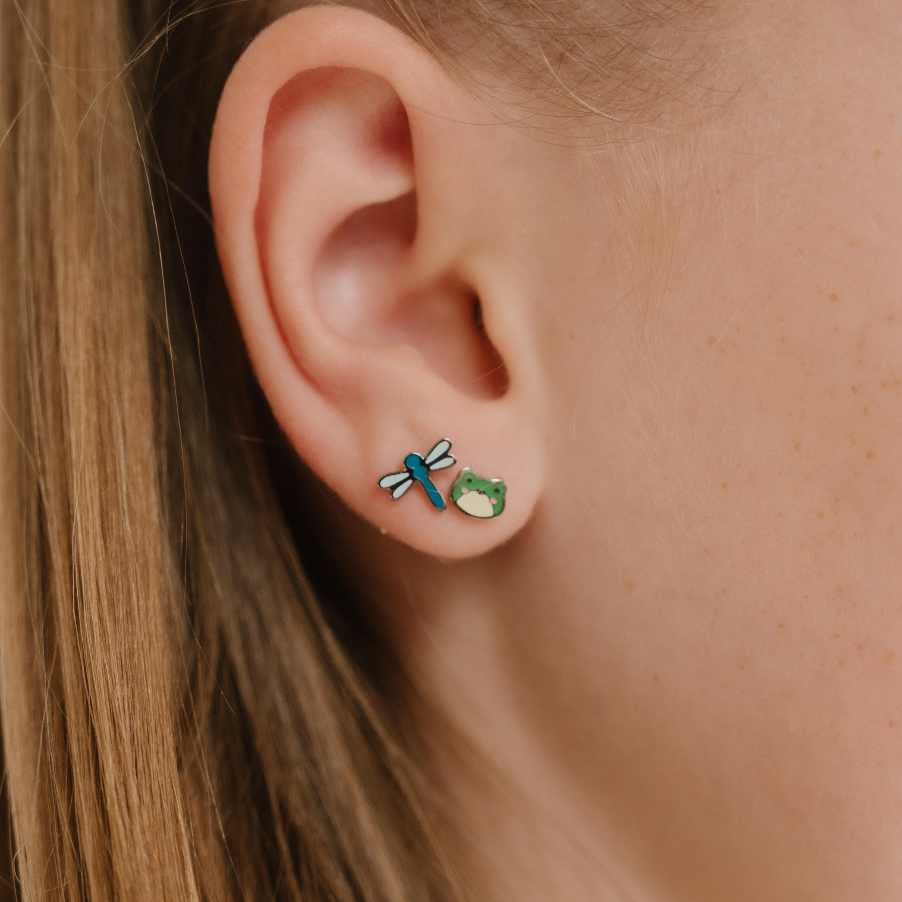A close up of a frog shaped flat back stud with green enamel and titanium metal.