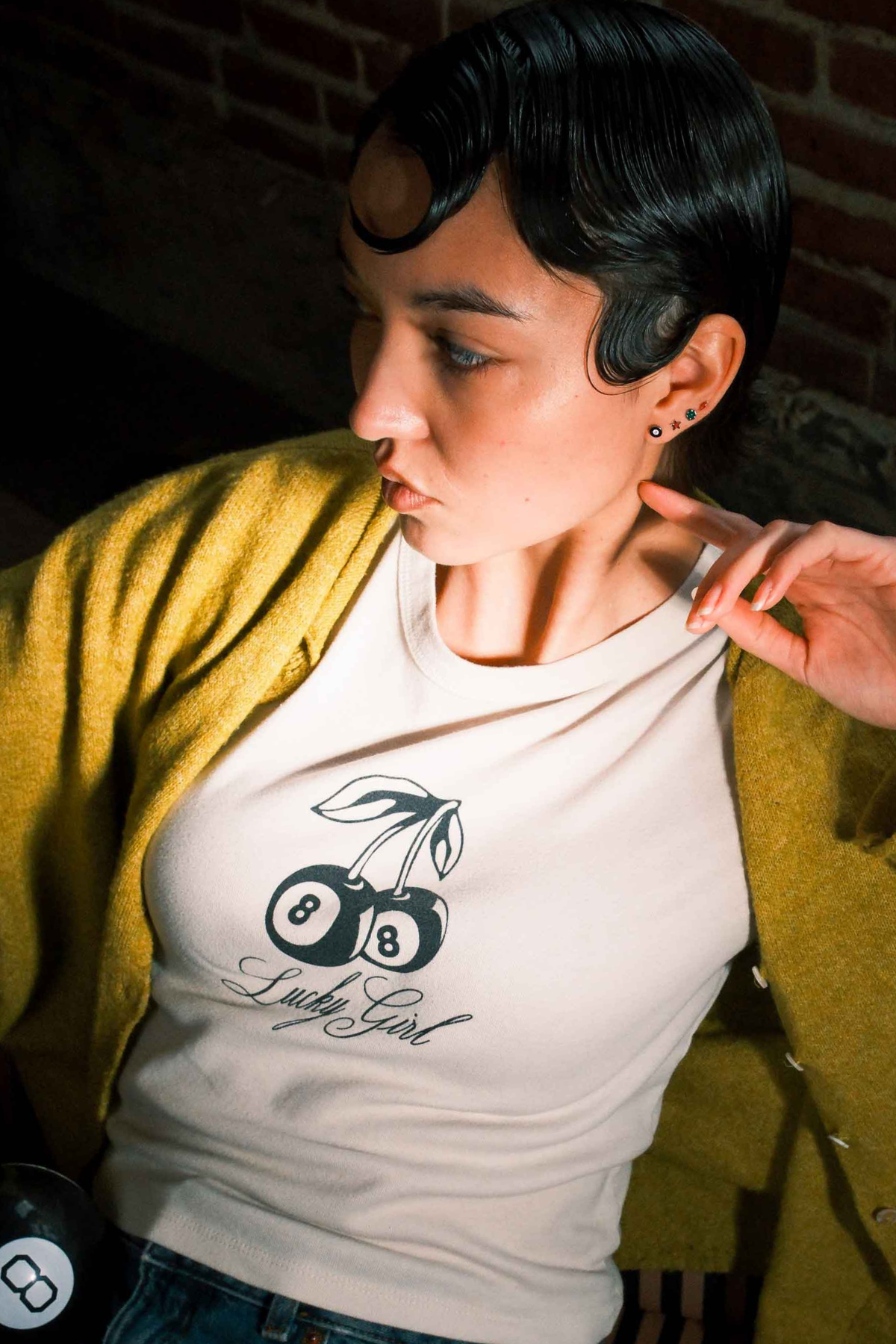 Person wearing multiple earrings in their ear, including a lightning bolt shaped flat back stud in cherry red.