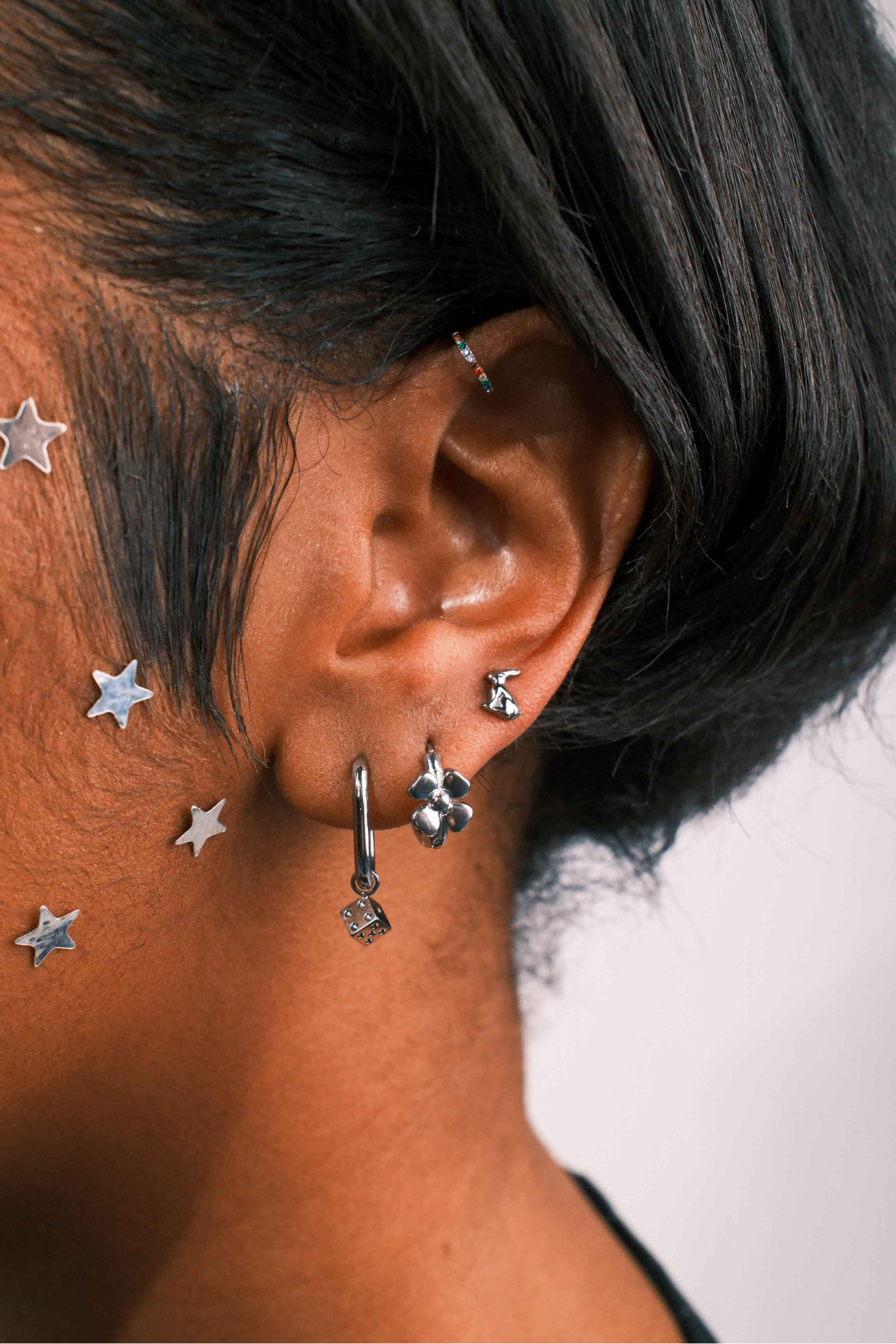 Close-up of an ear with multiple silver earrings against a blurred background
