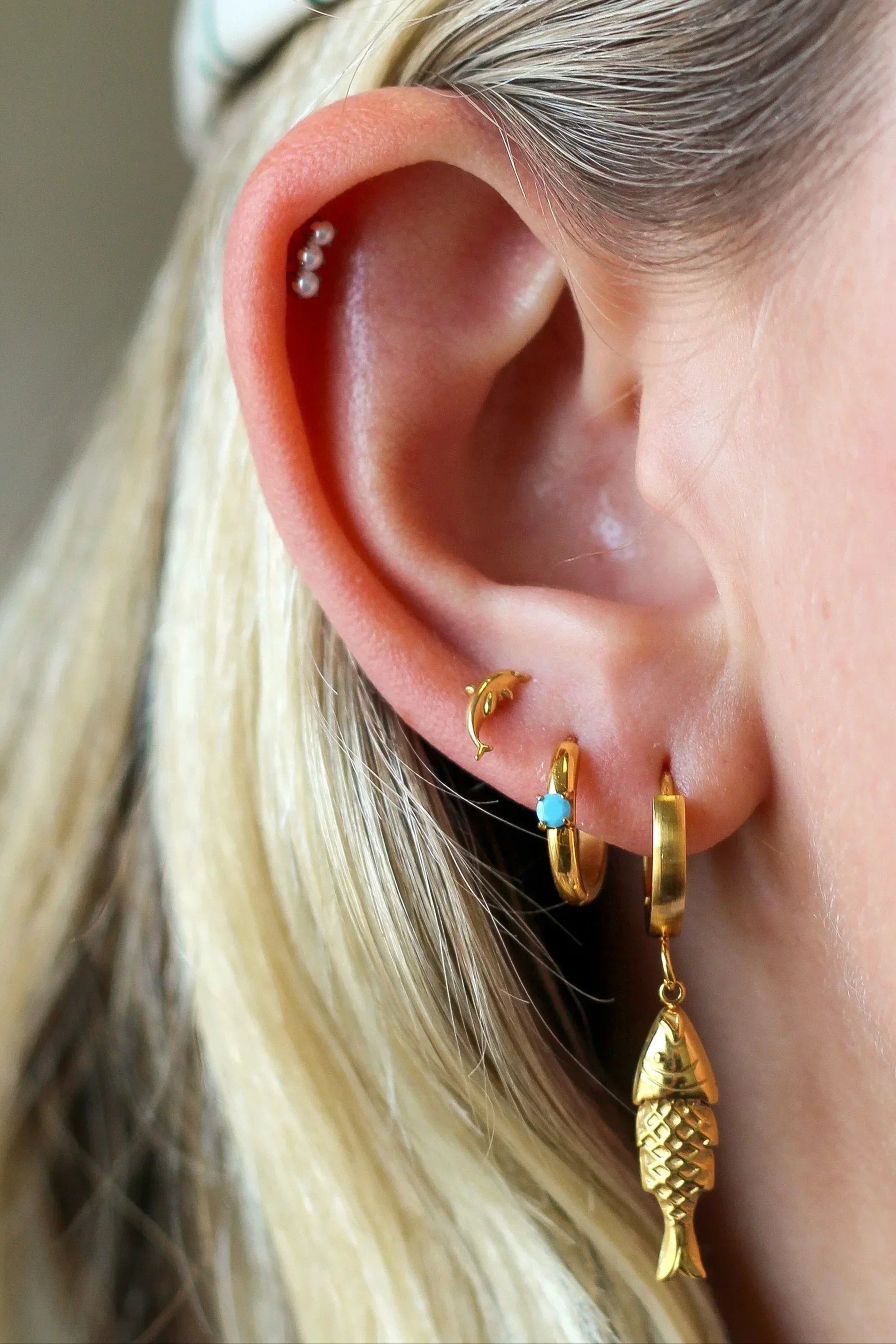 Close-up of an ear with gold earrings and a blurred background
