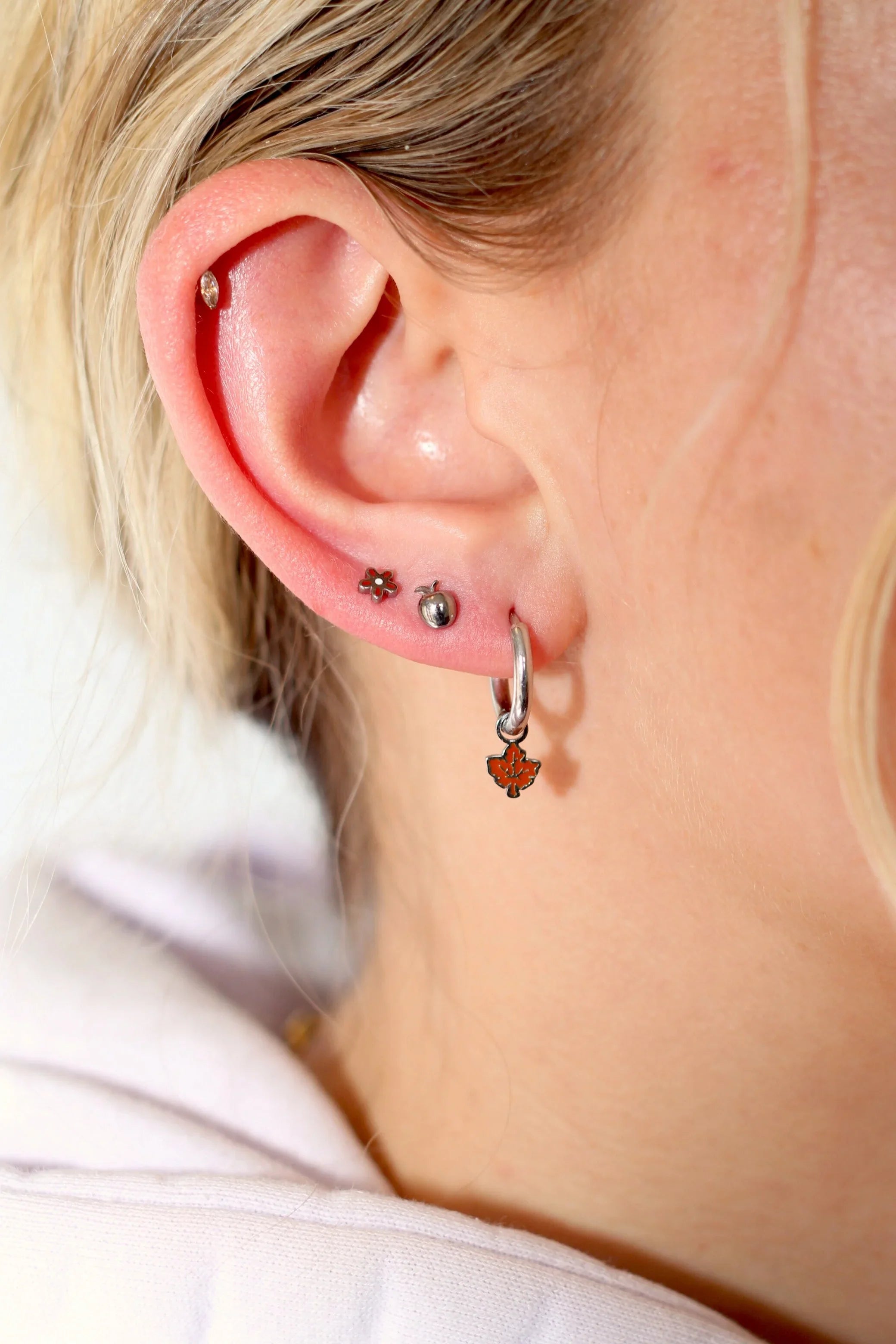 Close-up of a person's ear with multiple earrings.