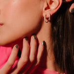 Close up of an ear with 2 sizes of gold and clear CZ hoops on it.