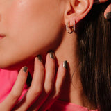 Close up of an ear with 2 sizes of gold and clear CZ hoops on it.