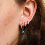 Close-up of an ear wearing multiple earrings with a blurred background