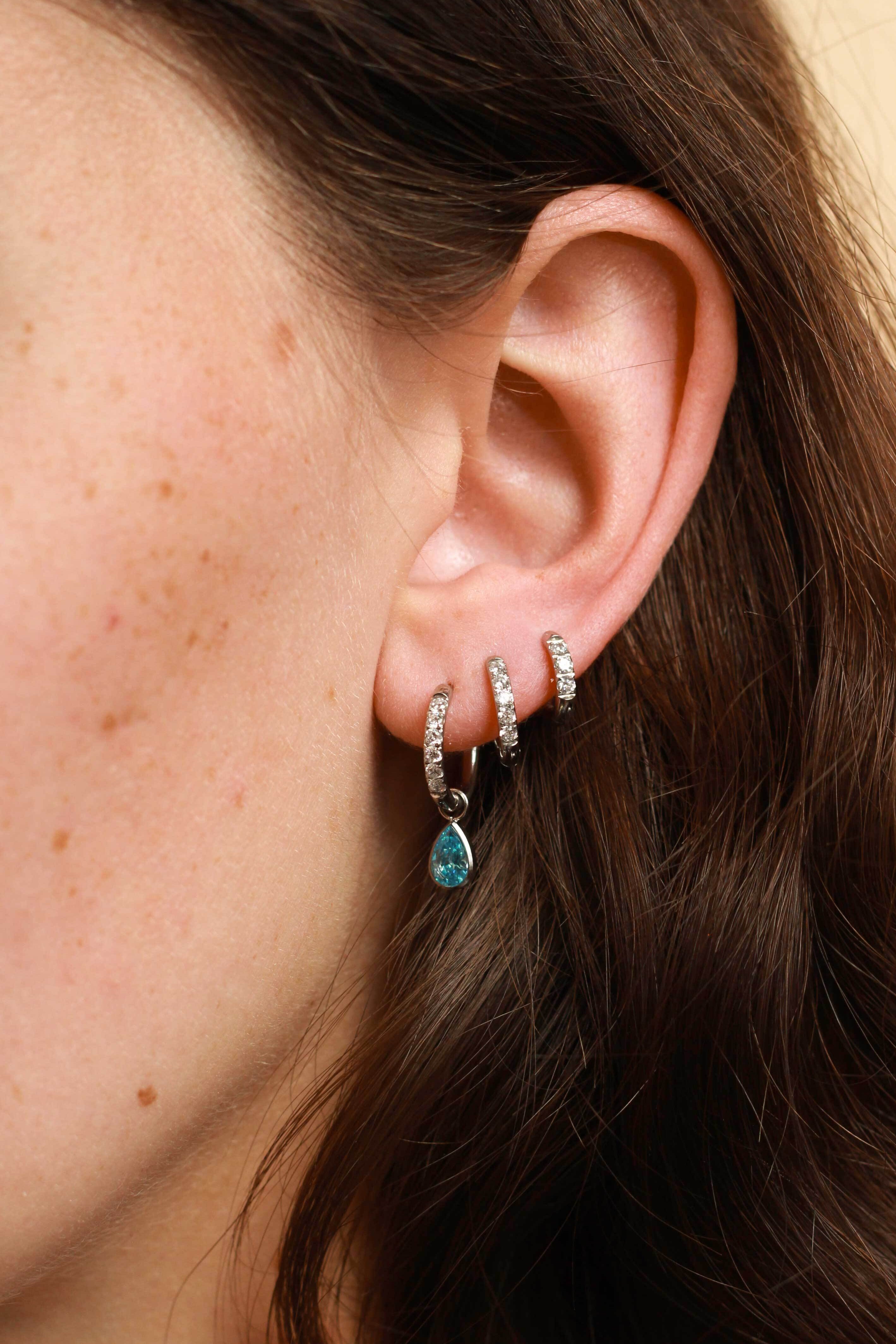 Close-up of an ear wearing multiple earrings with a blurred background