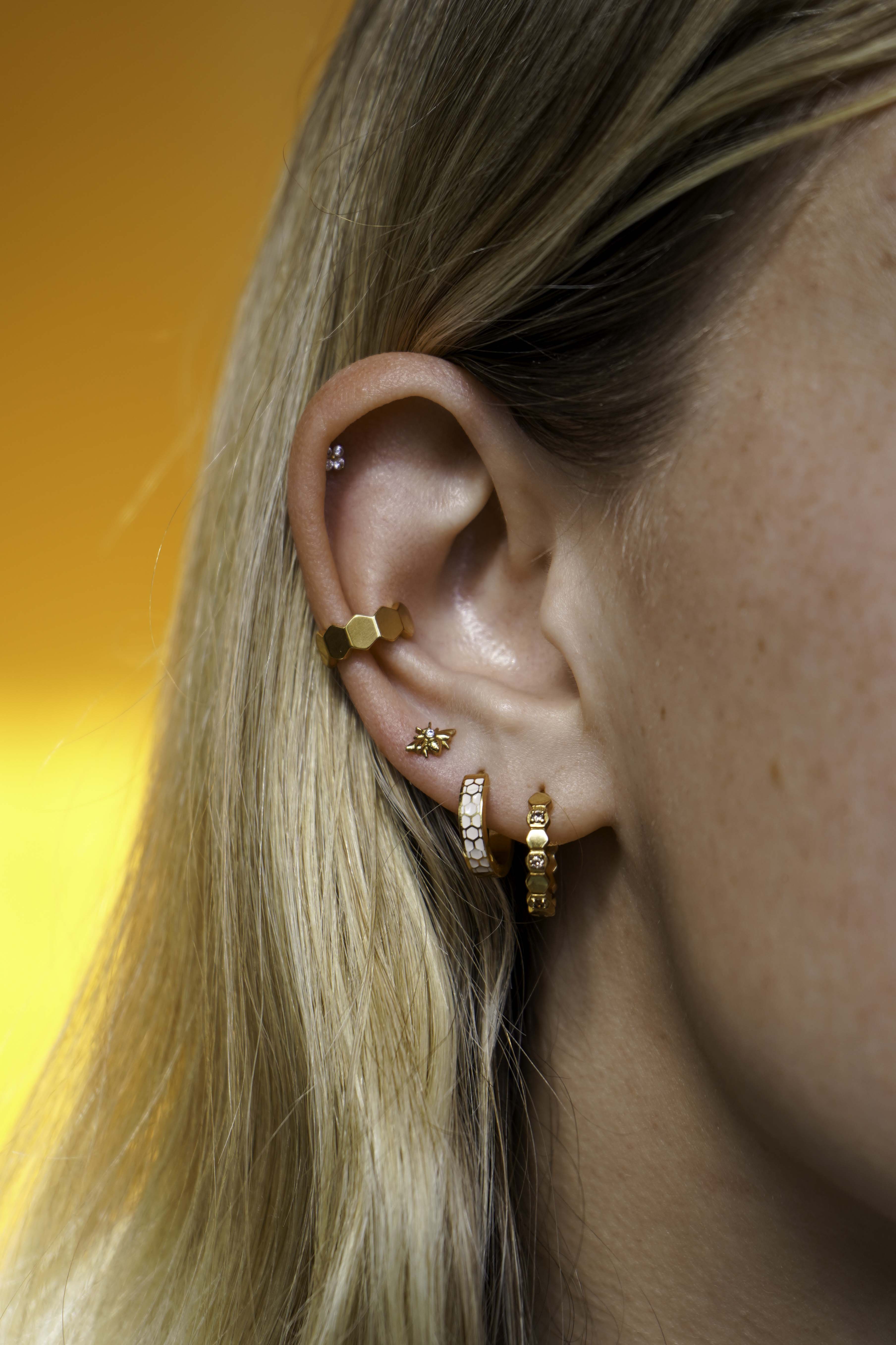Close up of a model wearing a cuff earring made from stacked hexagon shapes. Hoop made from stainless steel.