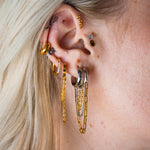 Close-up of an ear with multiple gold hoop earrings and a blurred background
