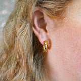 Close-up of a person wearing a gold hoop earring with a blurred background