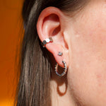 Close up of a model wearing a cuff earring made from stacked hexagon shapes. Hoop made from 18k gold-plated stainless steel.