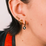 Close-up of an ear wearing gold earrings with a blurred background