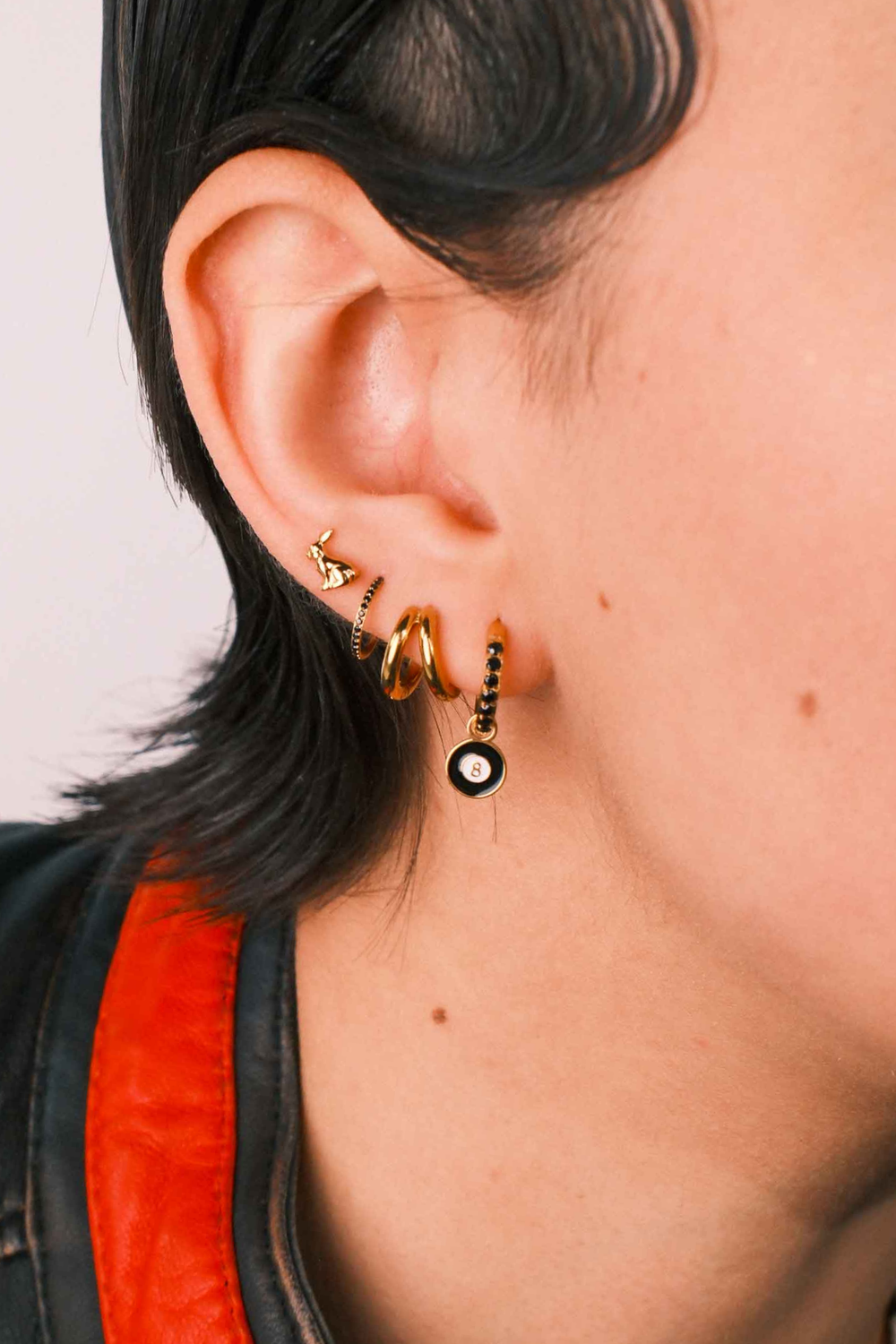 Close-up of an ear wearing gold earrings with a blurred background
