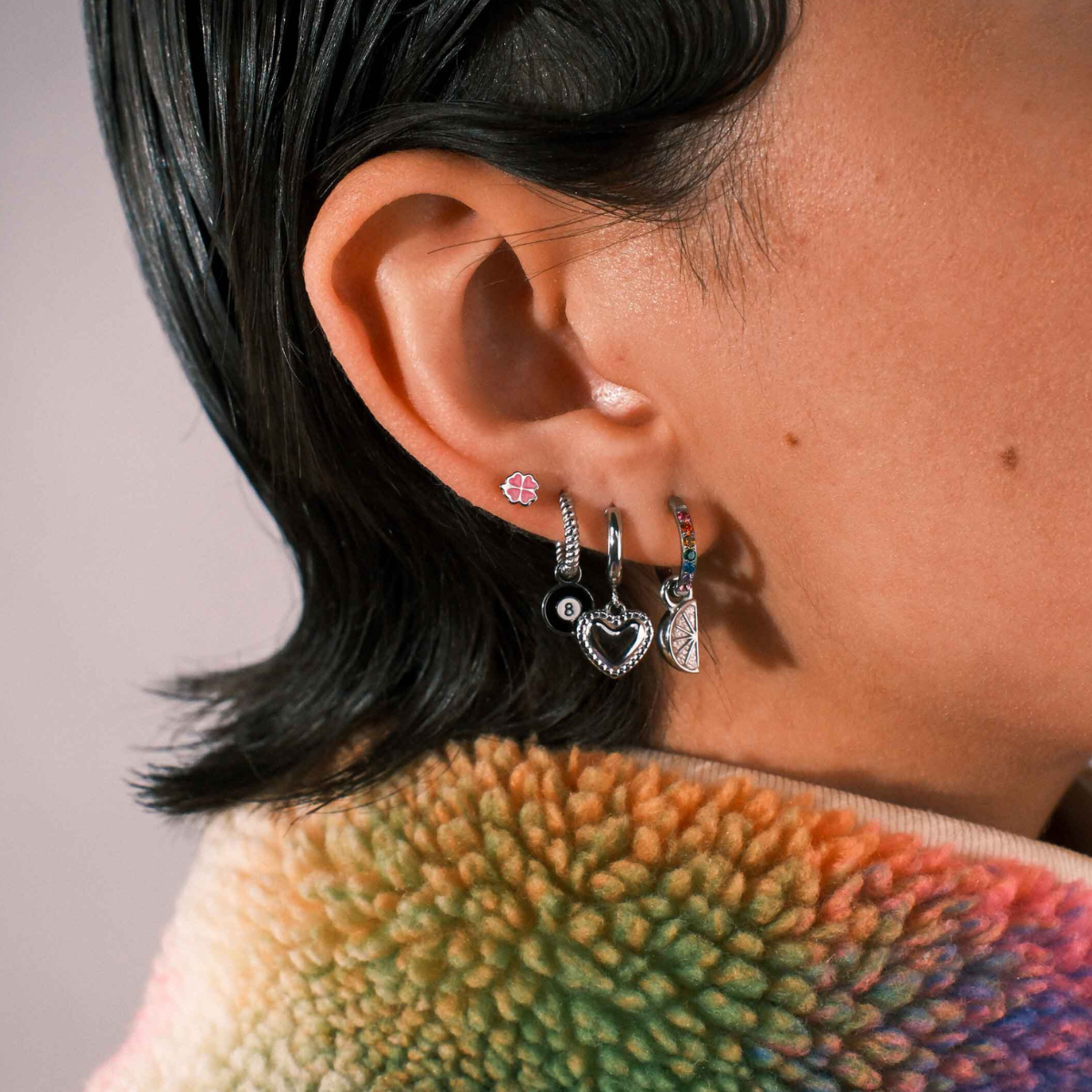 Close-up of an ear with multiple earrings against a blurred background