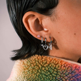 Close-up of an ear with multiple earrings against a blurred background