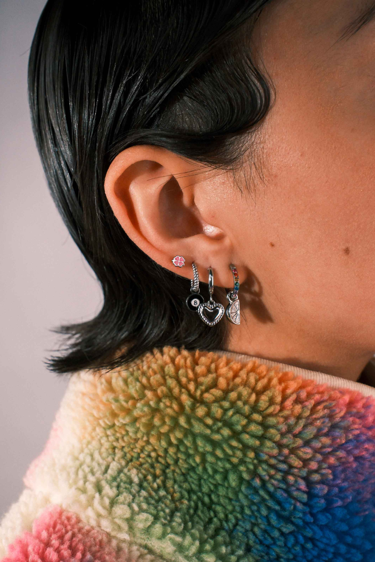 Close-up of an ear with multiple earrings against a blurred background
