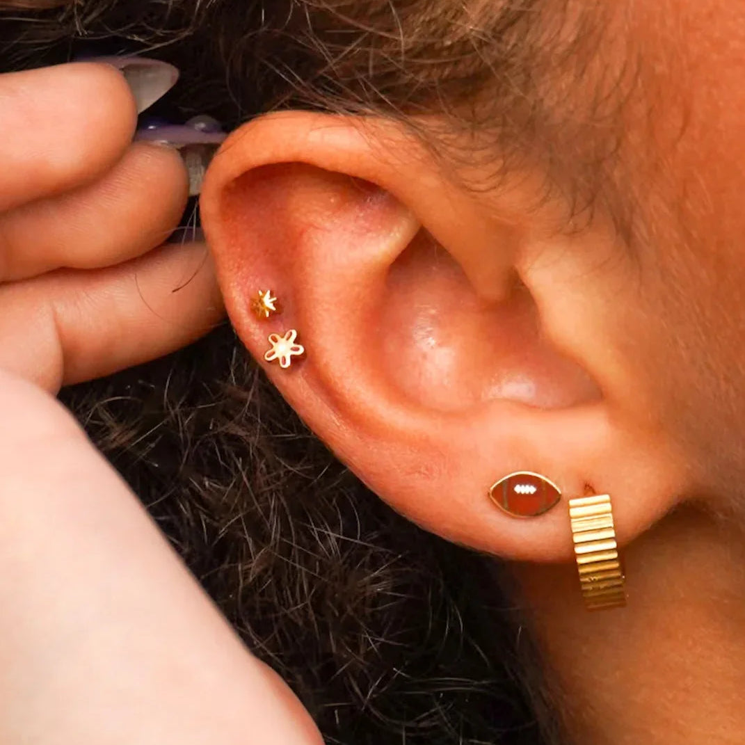 Close-up of an ear with gold earrings against a blurred background