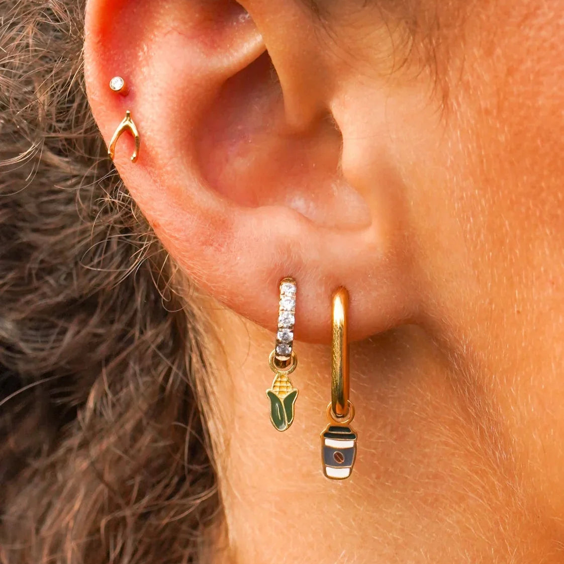 Close-up of an ear with gold hoop earrings and a small stud earring.