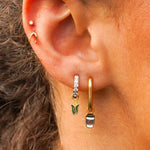 Close-up of an ear with gold hoop earrings and a small stud earring.