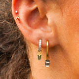 Close-up of an ear with gold hoop earrings and a small stud earring.