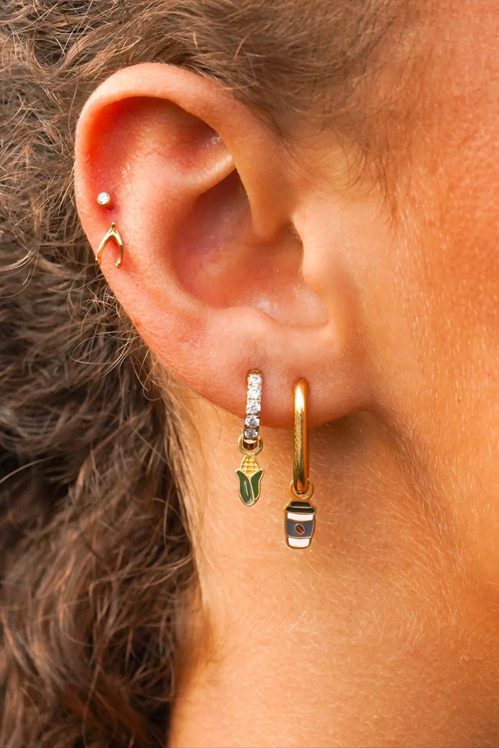 Close-up of an ear with gold hoop earrings and a small stud earring.