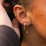 Close-up of an ear with earrings and a hand adjusting hair.
