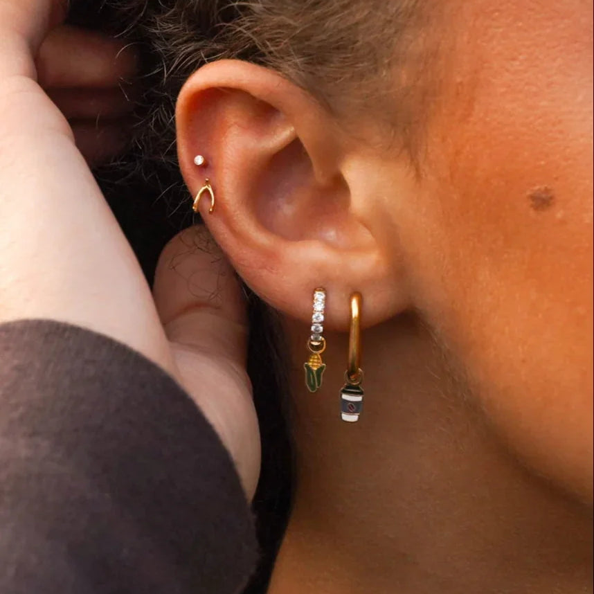 Close-up of an ear with earrings and a hand adjusting hair.
