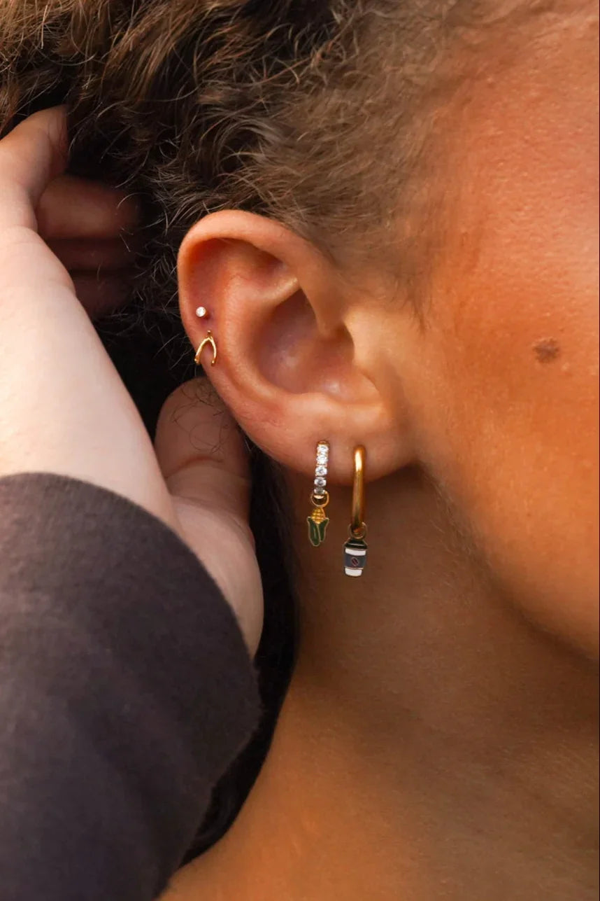 Close-up of an ear with earrings and a hand adjusting hair.