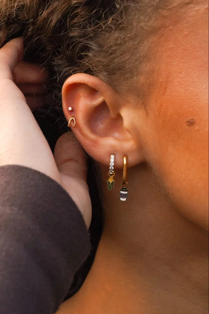 Close-up of an ear with earrings and a hand adjusting hair.