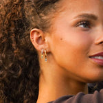 Close-up of a woman wearing gold hoop earrings with a blurred background