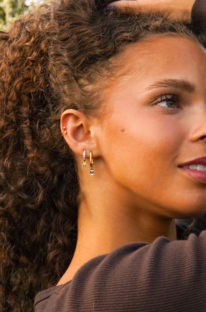 Close-up of a woman wearing gold hoop earrings with a blurred background