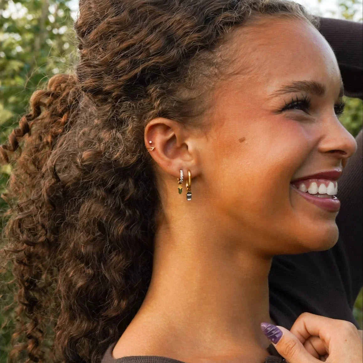 Woman with curly hair smiling outdoors