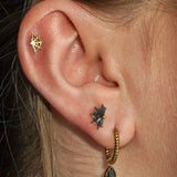 Close-up of an ear with gold and black earrings