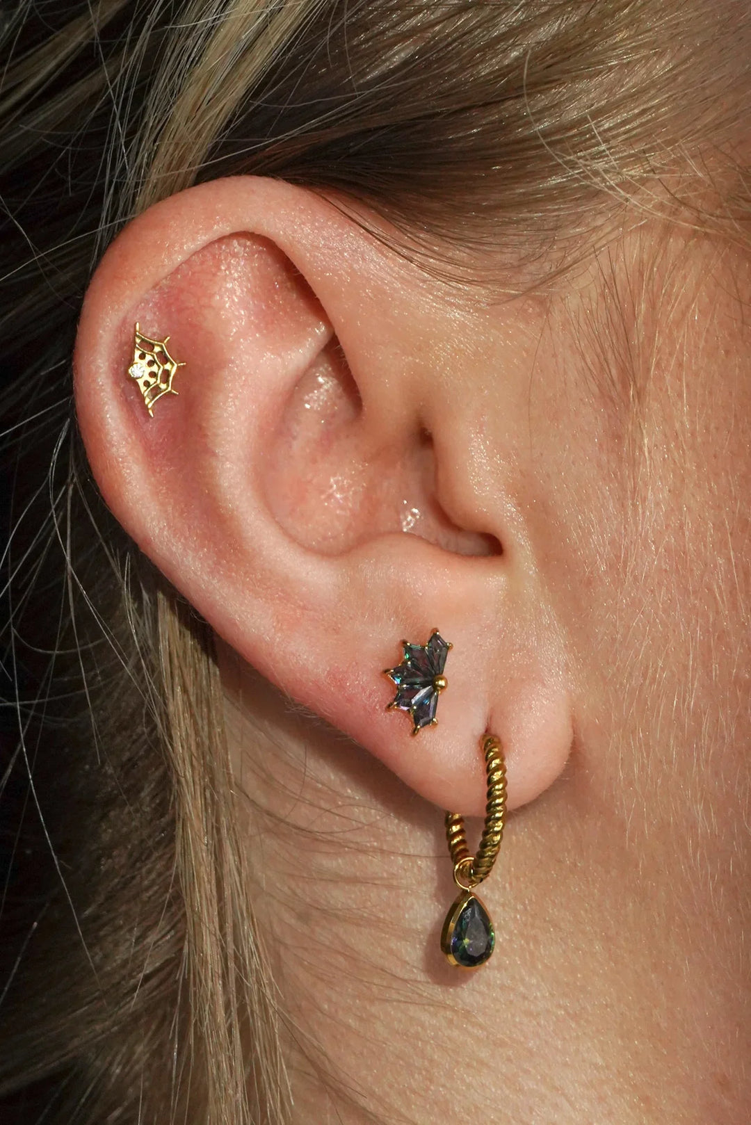 Close-up of an ear with gold and black earrings