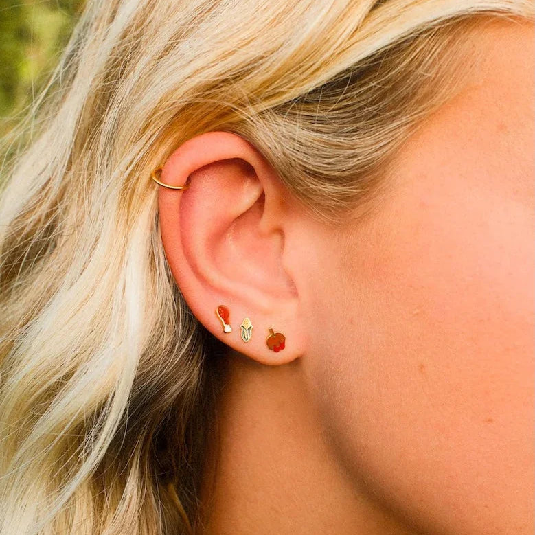 Close-up of a person wearing earrings with a blurred natural background