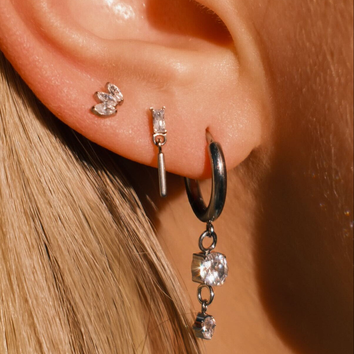 Close-up of an ear wearing multiple earrings with a blurred background