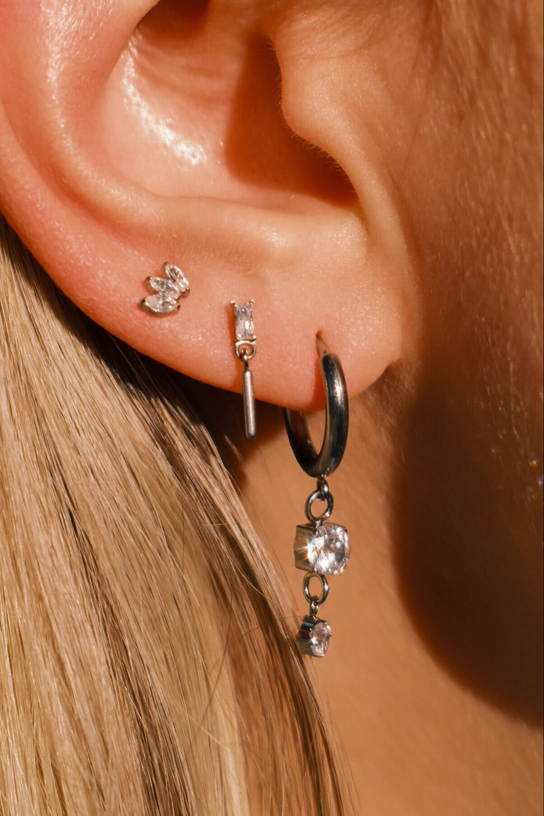 Close-up of an ear wearing multiple earrings with a blurred background