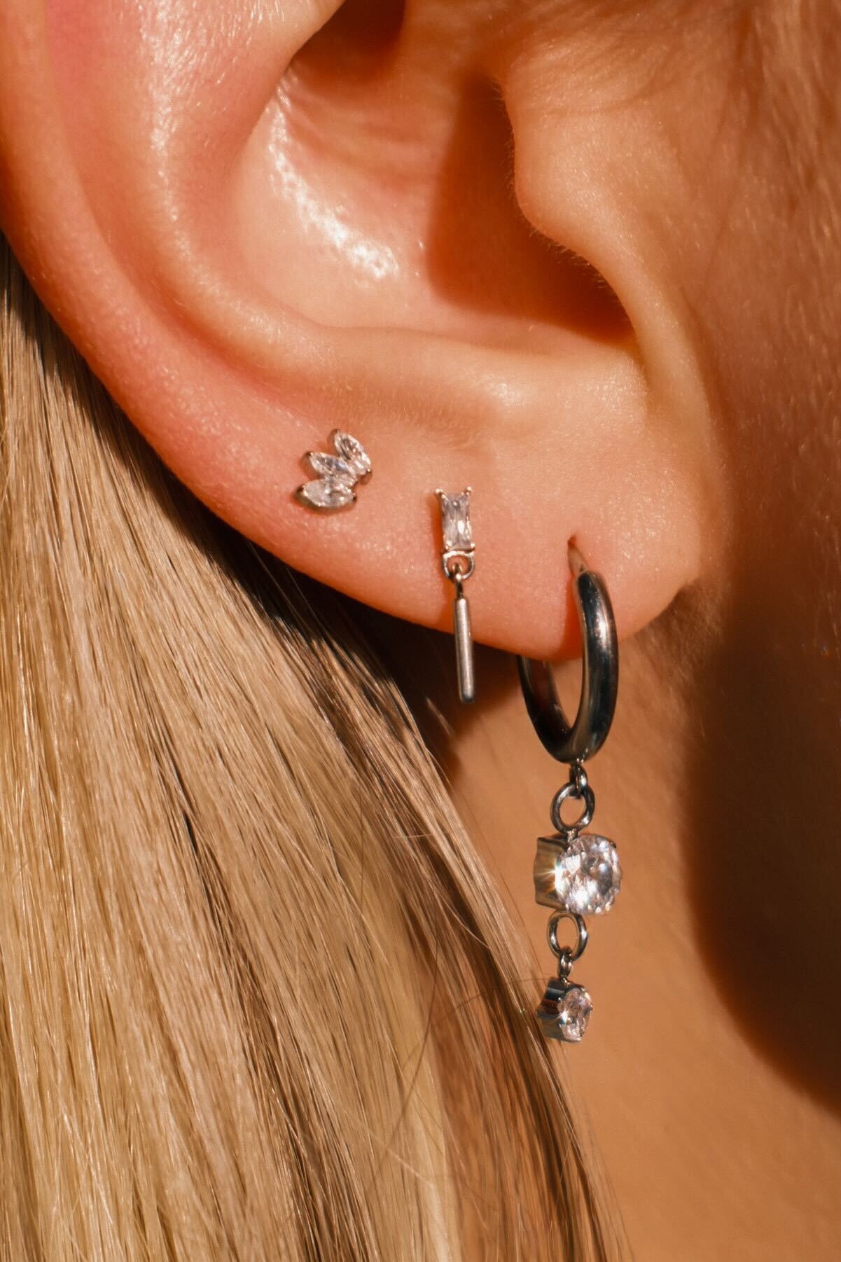 Close-up of an ear wearing multiple earrings with a blurred background