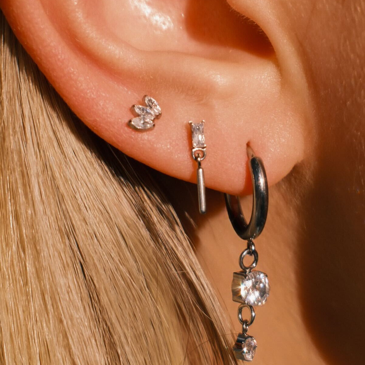 Close-up of an ear wearing multiple earrings with a blurred background