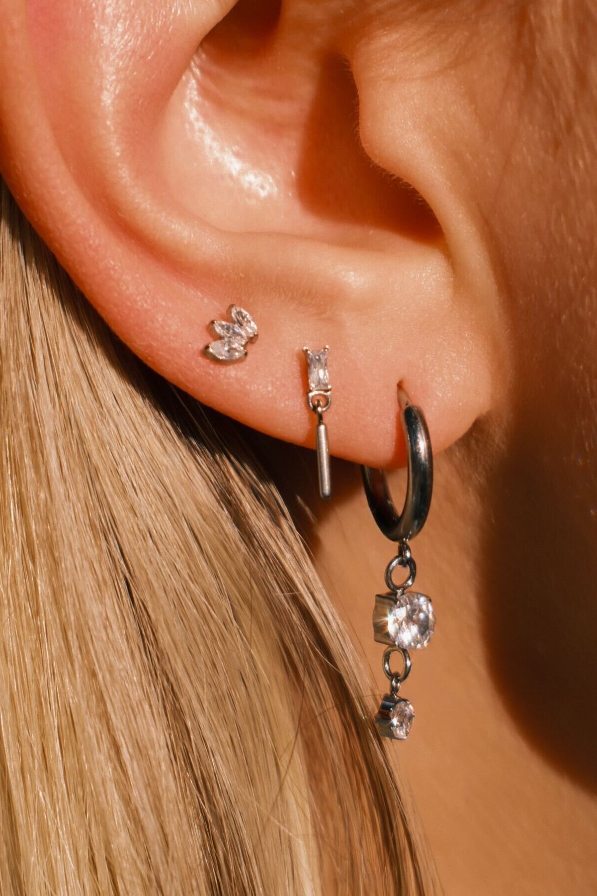 Close-up of an ear wearing multiple earrings with a blurred background