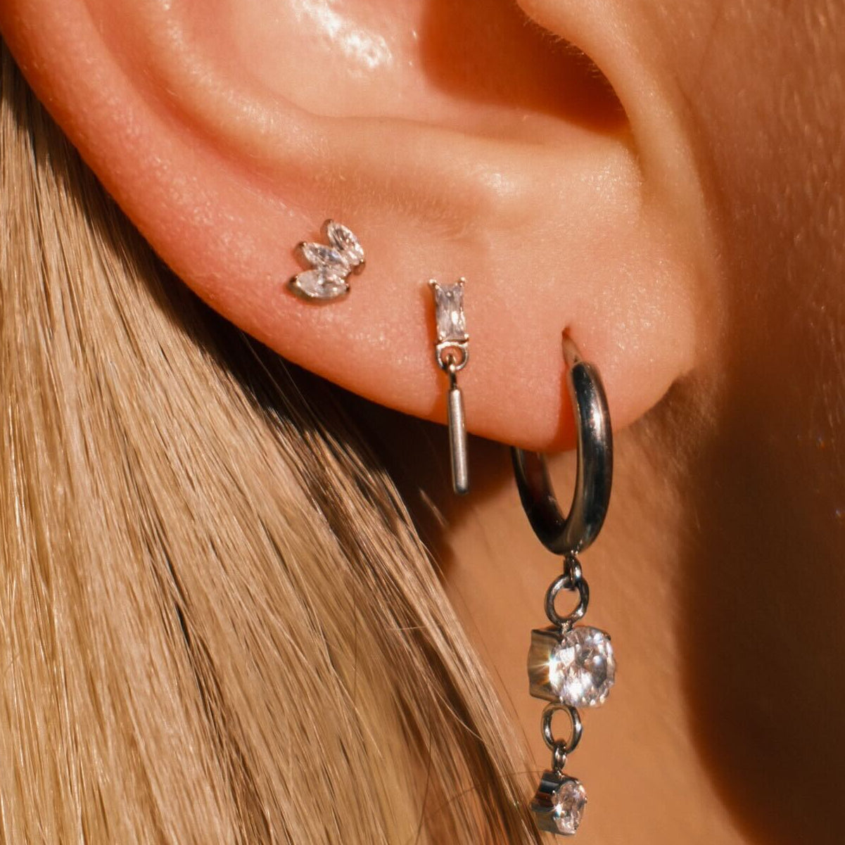 Close-up of an ear wearing multiple earrings with a blurred background