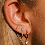 Close-up of an ear with multiple earrings against a blurred background