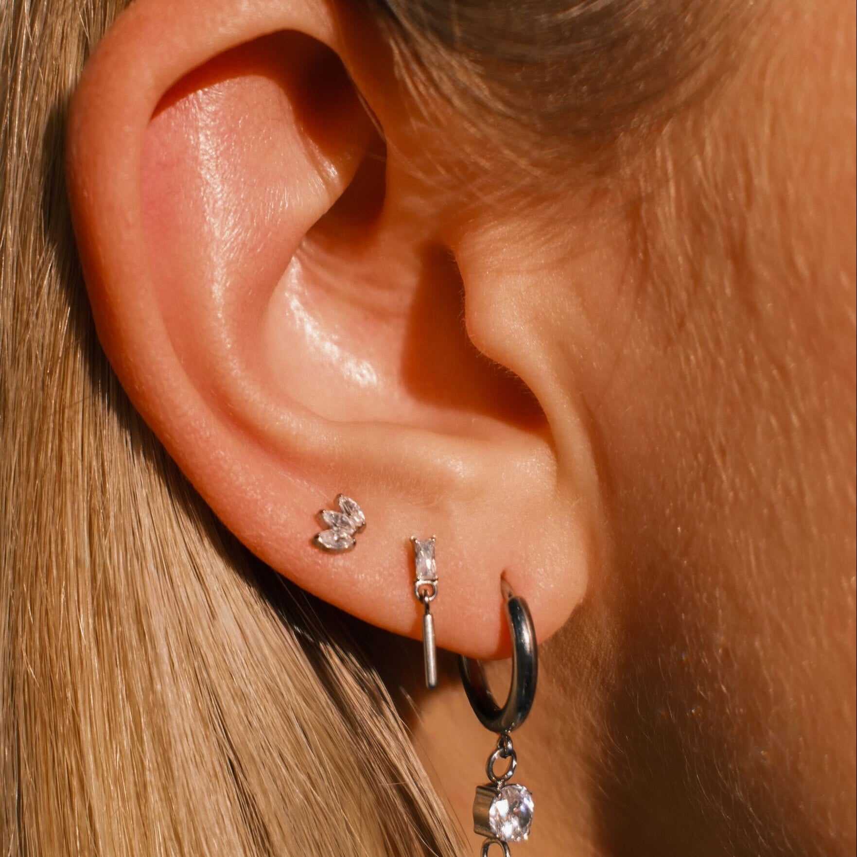 Close-up of an ear with multiple earrings against a blurred background