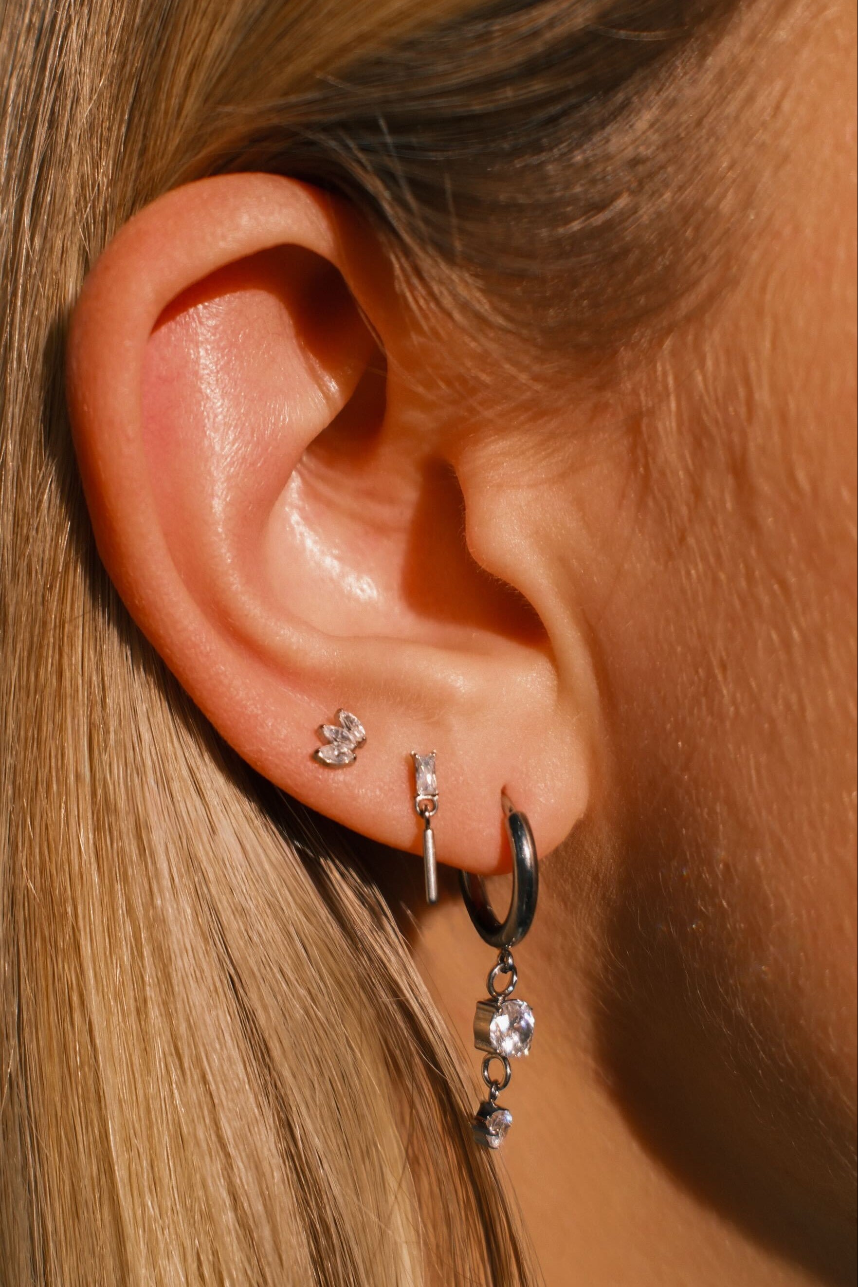 Close-up of an ear with multiple earrings against a blurred background