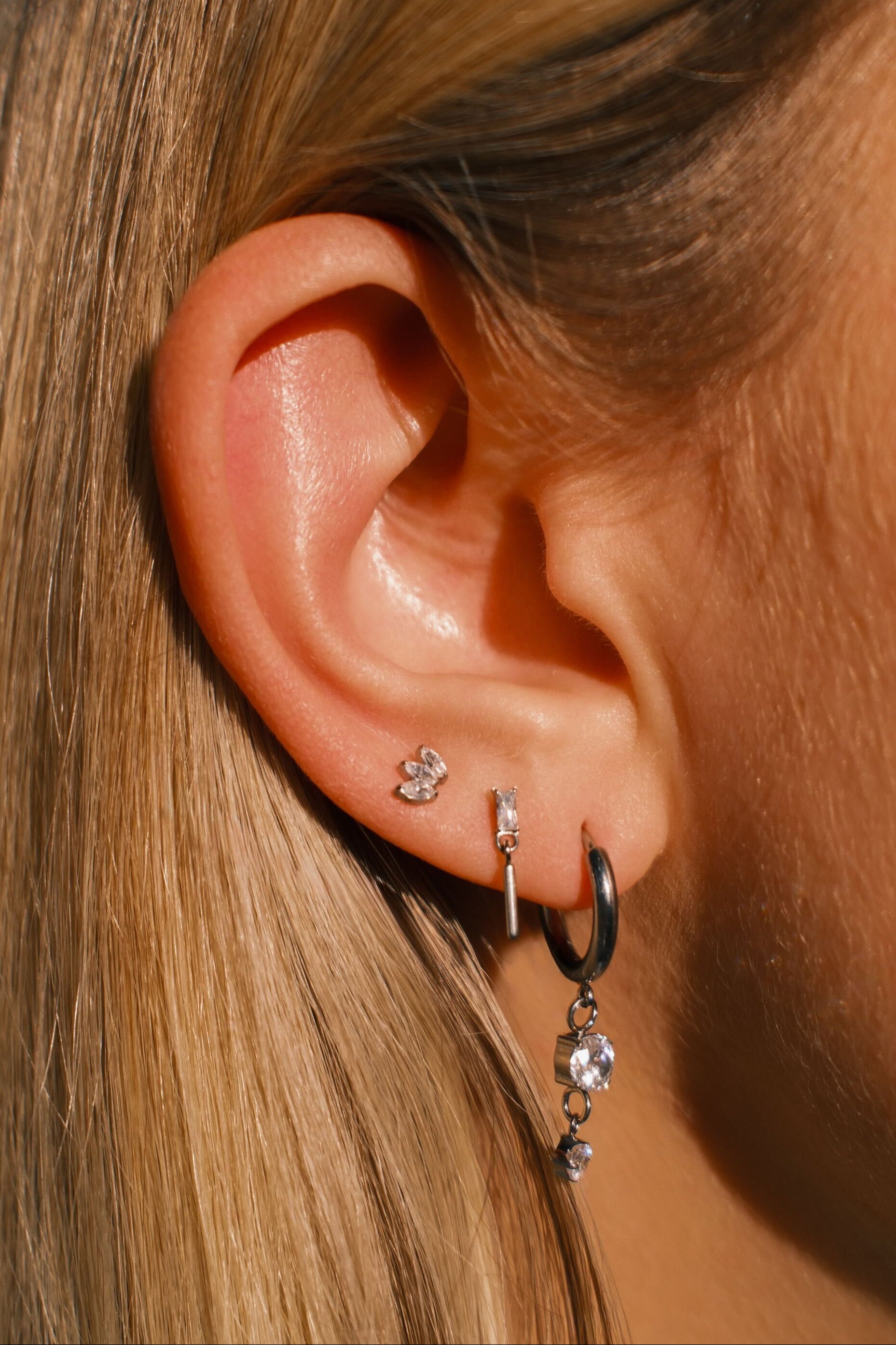 Close-up of an ear with multiple earrings against a blurred background