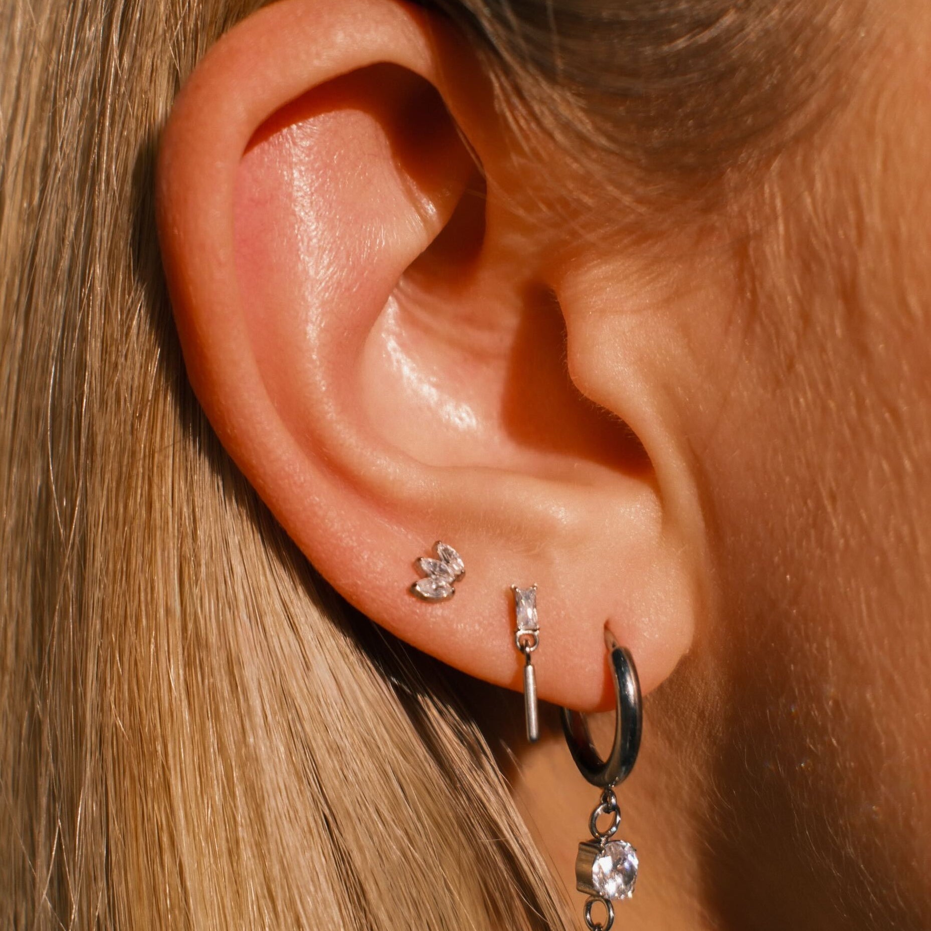Close-up of an ear with multiple earrings against a blurred background