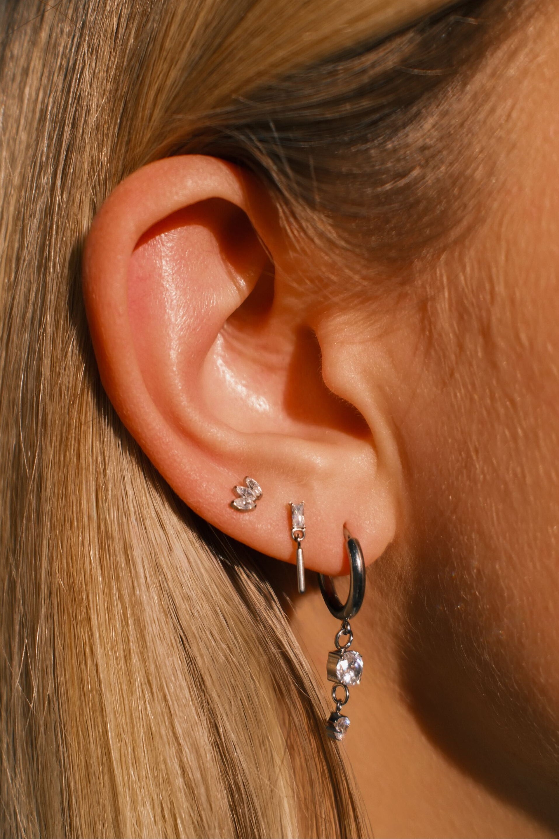 Close-up of an ear with multiple earrings against a blurred background