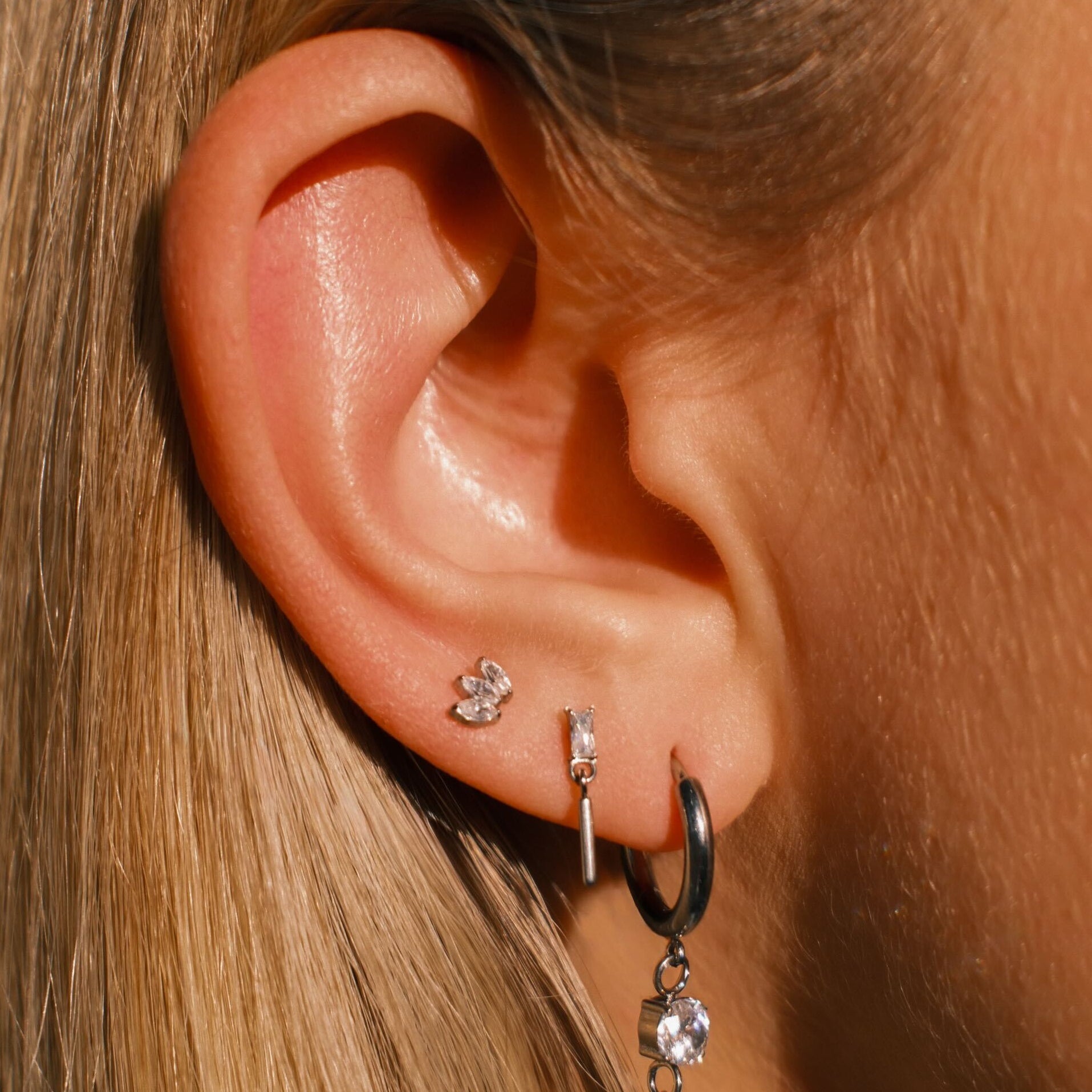 Close-up of an ear with multiple earrings against a blurred background
