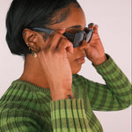 Person wearing multiple earrings against a plain background
