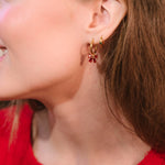 Close-up of a woman wearing gold earrings with a red background