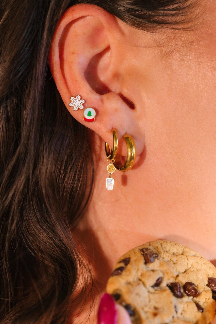 Close-up of an ear with gold hoop earrings and a cookie in the foreground